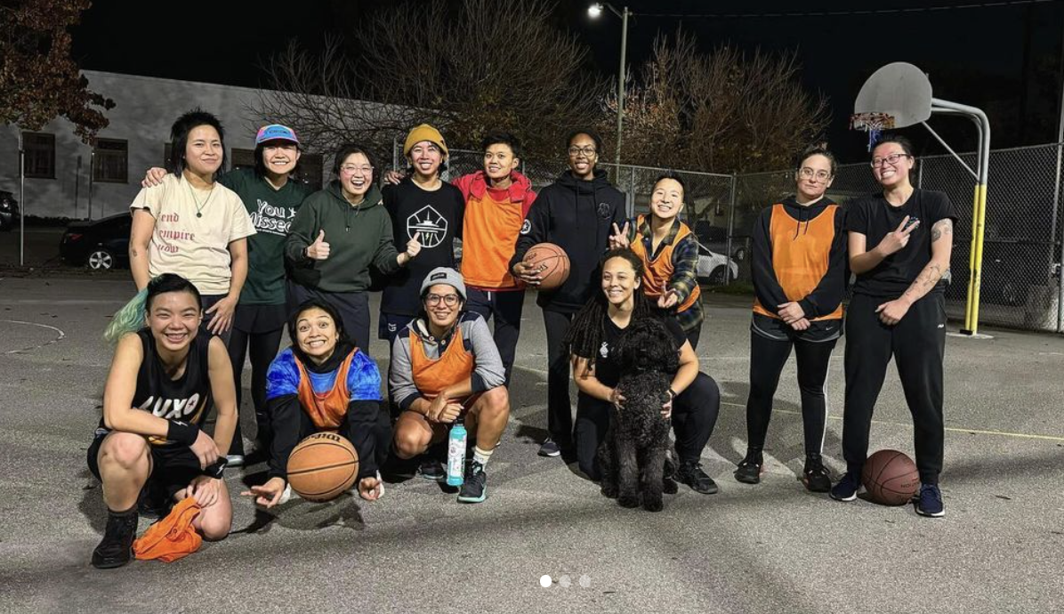 Group photo of members with basketballs on an outdoor court at night